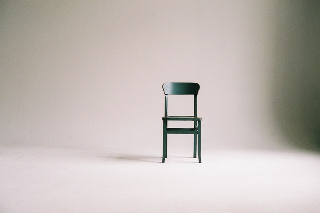 simple white desk on a white wall with a plant on the far right side